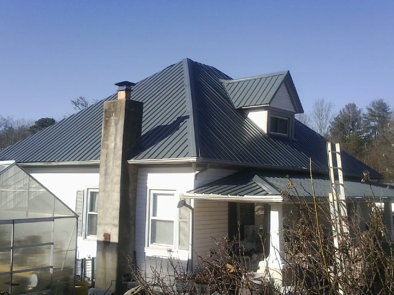 Dark blue standing seam metal roof on a white farmhouse with dormer — Slate & Tile Roof Repair by Roofing Brothers in Lodi